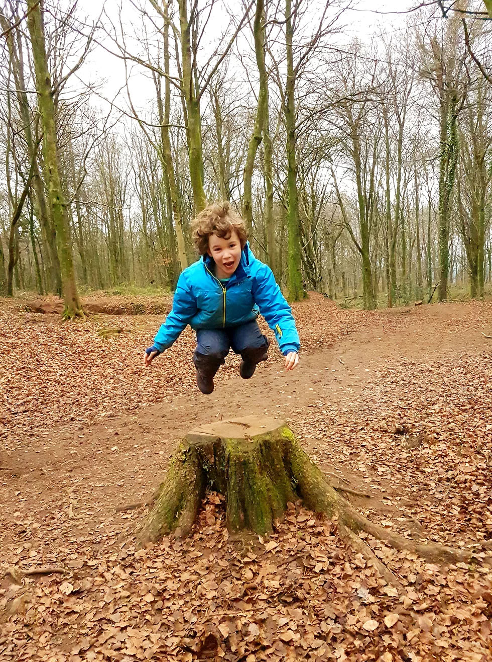 child leaping over a stump